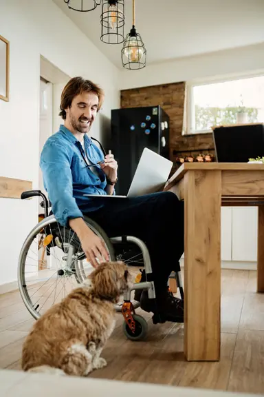 Osoba niepełnosprawna na wózku głaszcze psa